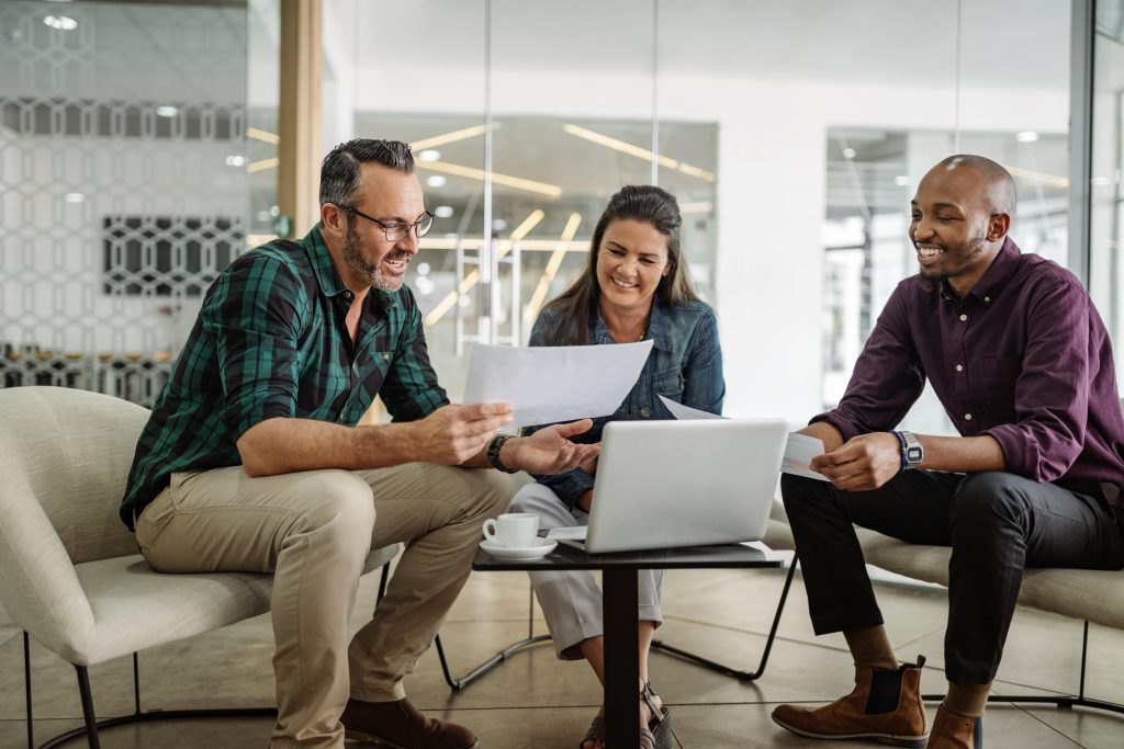 Three smiling employees discussing business over a laptop