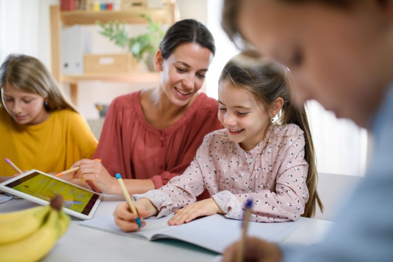 Children learning to write with the help of a teacher