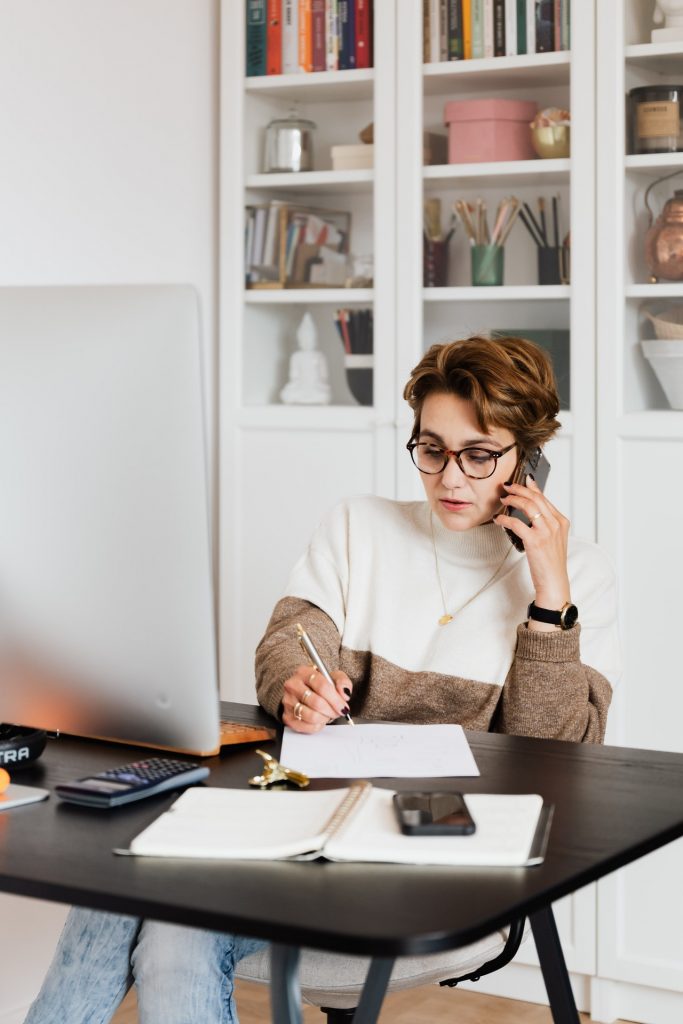Woman on the phone, making notes while working for her small business