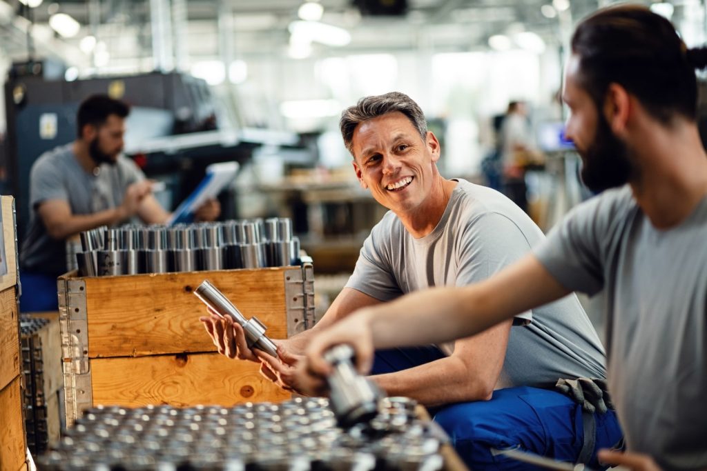 Men working in manufacturing smiling and conversing