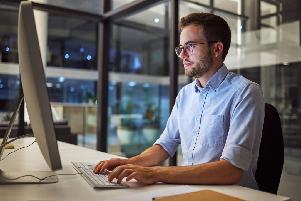 Young man typing on a desktop computer.