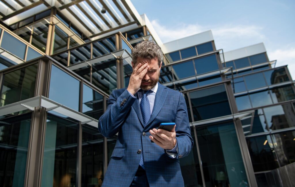Business man looking at his phone as he is receiving many push notifications