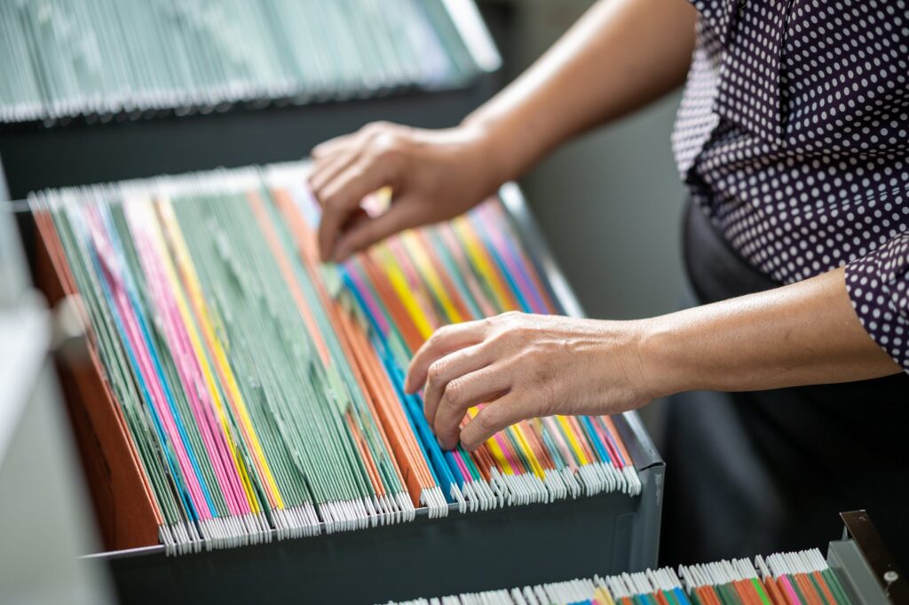 Woman's hand searching for documents at the filing cabinet